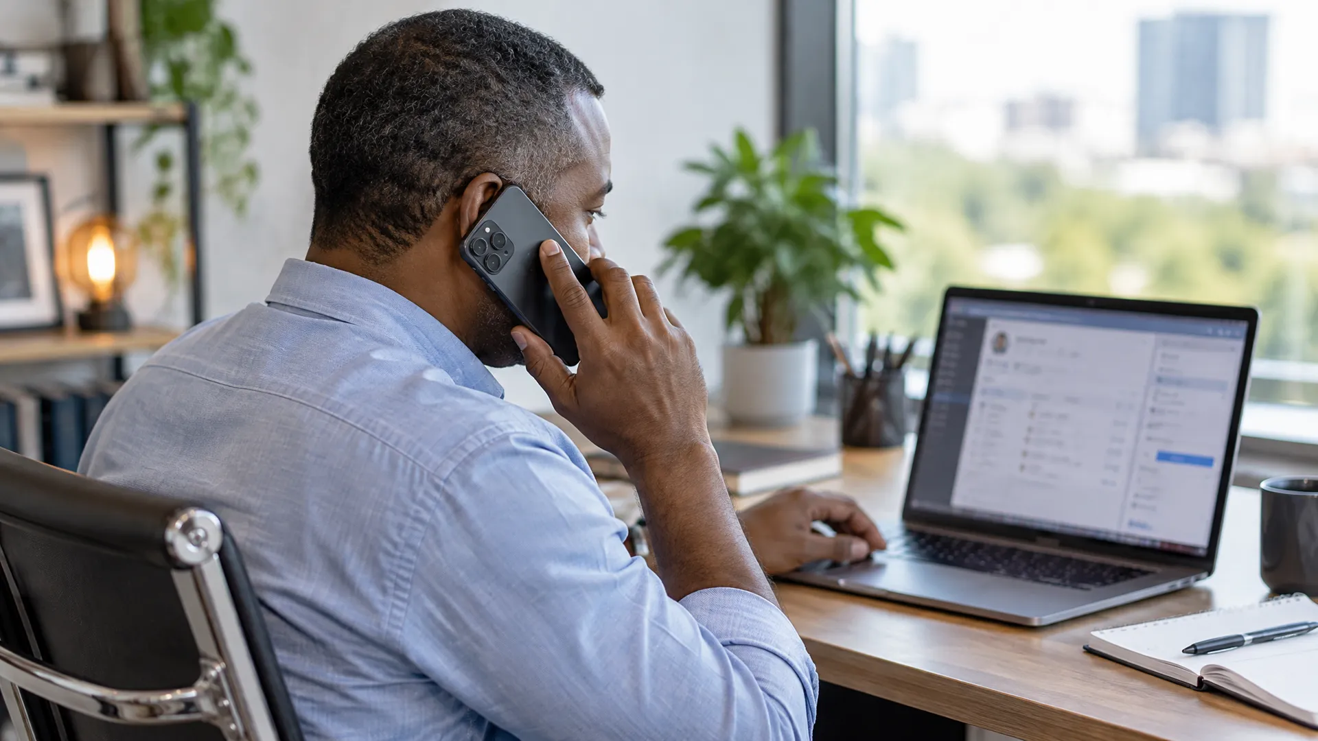 Small business owner following up with a lead by phone, using CRM notes beside his laptop to turn social media leads into customers